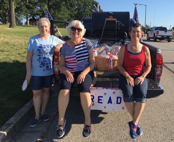Friends of the Library members sitting on the back of a truck during a fundraiser.